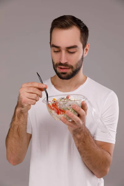 Um homem come tigela vegan com pauzinhos. Um homem segura tigela de picada em suas mãos — Fotografia de Stock