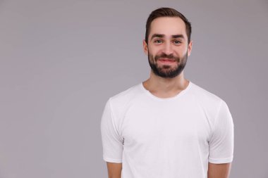 gri bir arka plan üzerinde beyaz bir T-shirt bir sakallı bir adam