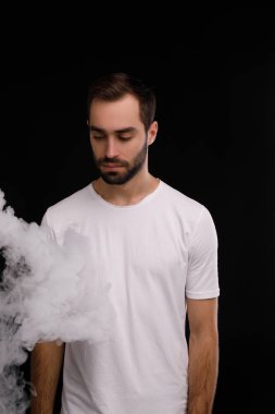 Siyah bir zemin üzerine beyaz T-shirt giyen dumana görünüyor