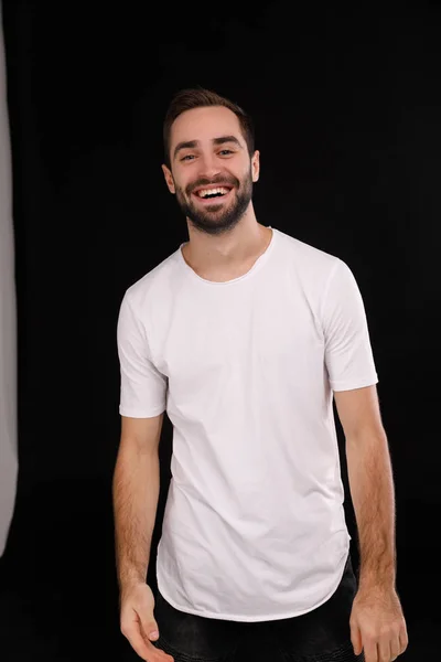 Cara alegre em uma camiseta branca em um fundo preto — Fotografia de Stock