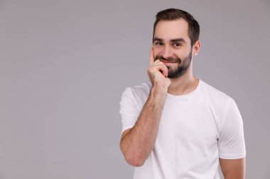 Gri bir arka plan üzerinde beyaz bir T-shirt bir düşünme adam portresi.