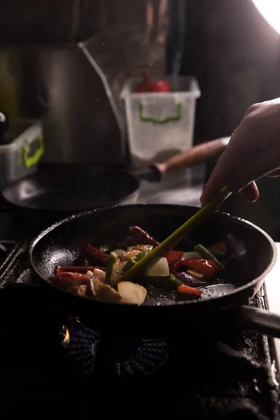 Šéfkuchař v restauraci Kitchen připravuje jídlo tmavé pozadí — Stock fotografie