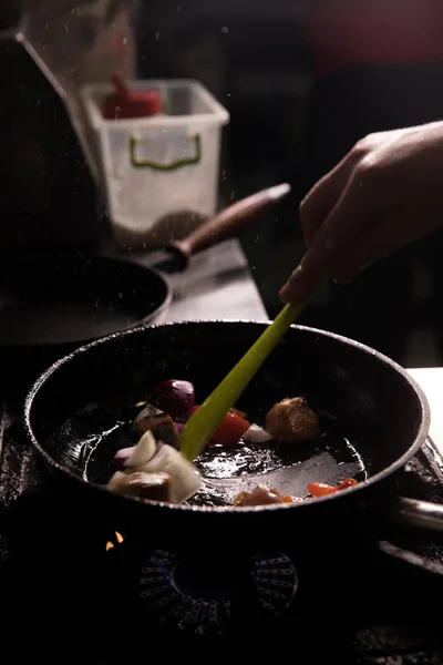 Šéfkuchař v restauraci Kitchen připravuje jídlo tmavé pozadí — Stock fotografie