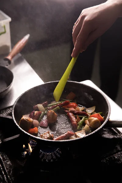 Šéfkuchař v restauraci Kitchen připravuje jídlo tmavé pozadí — Stock fotografie