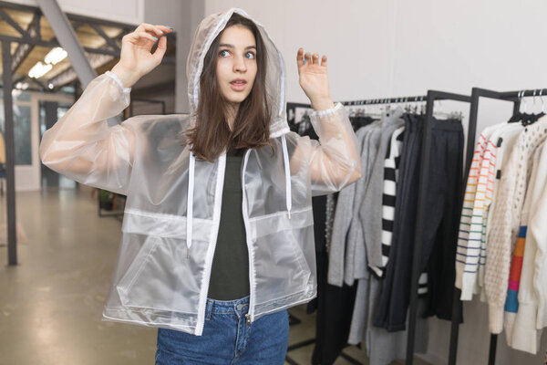 The girl in the store chooses a transparent jacket.