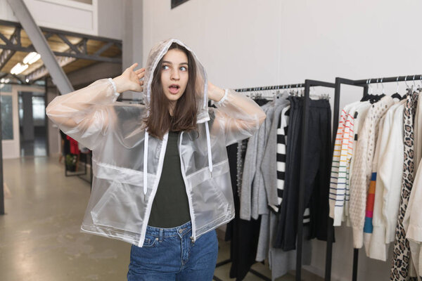 The girl in the store chooses a transparent jacket.