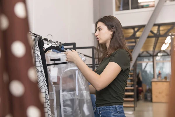 Η κοπέλα στο κατάστημα εξετάζει ένα διαφανές σακάκι. — Φωτογραφία Αρχείου