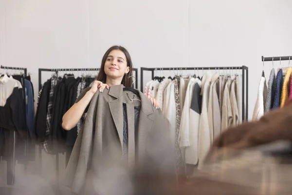 A young girl in a clothing store chooses a coat. — Stock Photo, Image