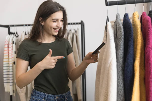 Молода дівчина в магазині одягу вибирає светр . — стокове фото