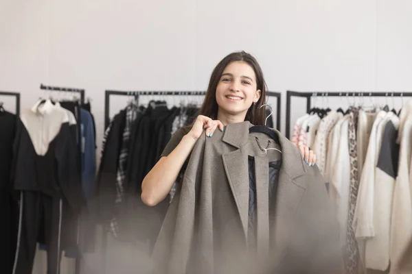 A young girl in a clothing store chooses a coat. — Stock Photo, Image