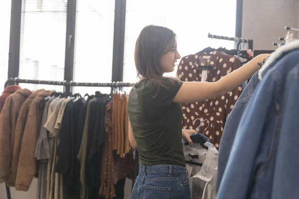 Дівчина в магазині одягу вибирає джинсову куртку — стокове фото