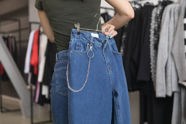 Dziewczyna w sklepie wybiera jego dżinsy. — Zdjęcie stockowe