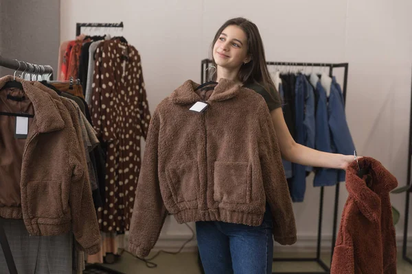 Το κορίτσι με το κατάστημα ειδών ένδυσης επιλέγει μεταξύ δύο γούνινα παλτά. — Φωτογραφία Αρχείου