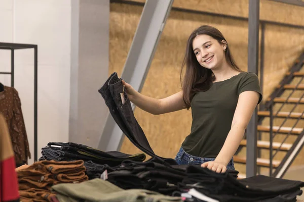Крупним планом дівчина вибирає чорні джинси в магазині . — стокове фото
