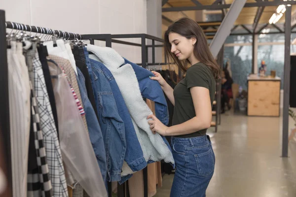 Дівчина в магазині одягу вибирає джинсову куртку — стокове фото