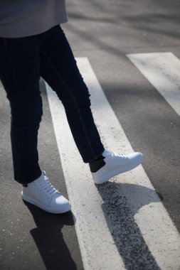 Genç adam bir karanlıkta pantolon ve spor ayakkabı yol geçtikten