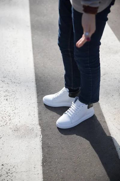 Ung man i en mörk byxor och sneakers som korsar vägen — Stockfoto