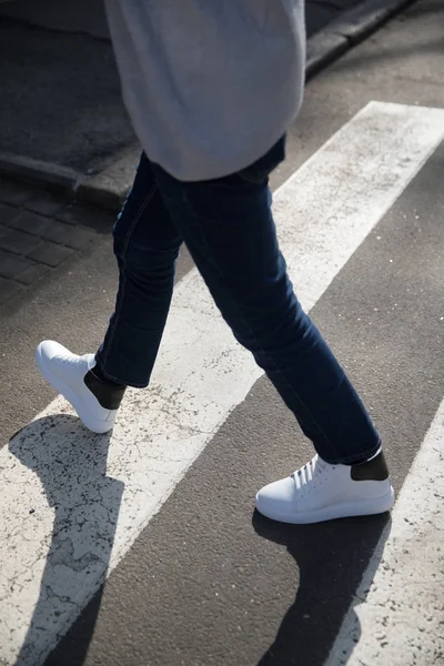 Νεαρός σε ένα σκούρο παντελόνι και αθλητικά παπούτσια που διασχίζουν το δρόμο — Φωτογραφία Αρχείου