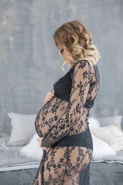 Mulher grávida em um belo vestido de renda mantém a barriga — Fotografia de Stock