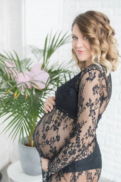 Mulher grávida em um belo vestido de renda mantém a barriga — Fotografia de Stock