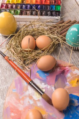 Paskalya yumurtalarını boyayan genç bir kadın, beyaz örtülü bir masa. Mutlu Paskalya tatili için hazırlık. Kadın elleri dekoratif renkli yumurtalar, el yapımı Paskalya zanaatı üst görünümü.