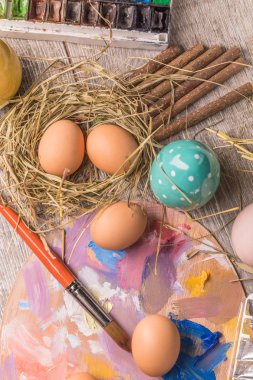 Paskalya yumurtalarını boyayan genç bir kadın, beyaz örtülü bir masa. Mutlu Paskalya tatili için hazırlık. Kadın elleri dekoratif renkli yumurtalar, el yapımı Paskalya zanaatı üst görünümü.