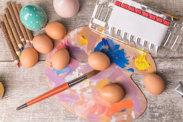 Paskalya yumurtalarını boyayan genç bir kadın, beyaz örtülü bir masa. Mutlu Paskalya tatili için hazırlık. Kadın elleri dekoratif renkli yumurtalar, el yapımı Paskalya zanaatı üst görünümü.