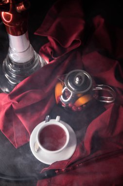 Cam bardak, masada, kırmızı arka planda çilek ile Meyve kırmızı çay. Süreç çay demleme, çay töreni, Taze demlenmiş meyve ve bitkisel çay, karanlık ruh kupası. Sıcak su çay yaprakları ile bir fincan içine su ısıtıcısı dökülür