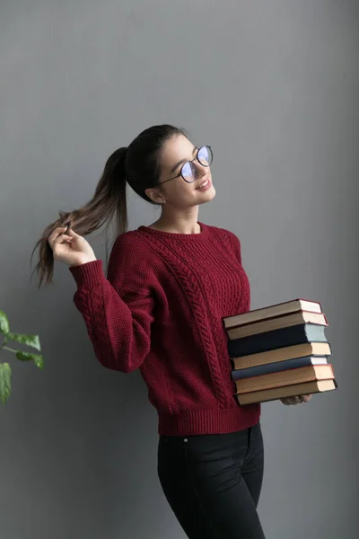 Cierre Una Niña Con Pelo Recogido Fondo Gris Con Libros —  Fotos de Stock