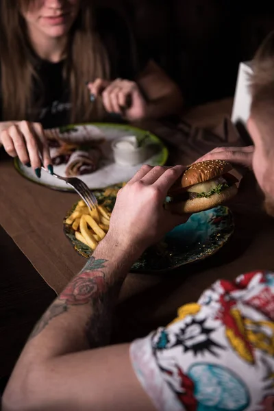Casal estão sentados à mesa e comer fast food. Conceito pouco saudável . — Fotografia de Stock