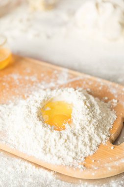 Pişirme konsepti. Rustik ahşap masa üzerinde gemide un ve yumurta sarısı, pişirme malzemeleri.
