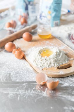 Pişirme konsepti. Rustik ahşap masa üzerinde gemide un ve yumurta sarısı, pişirme malzemeleri.