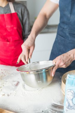 Ahşap arka plan üzerinde masaya kase içine un elemek. Genç kadın ahşap masanın üzerindeki bir elekten un emerek. T