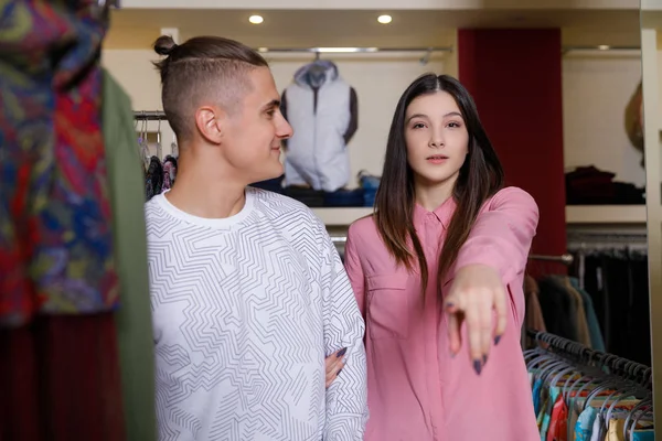 Det unga paret betraktar kläder i butik. Ungt trevligt par i butik med inköp — Stockfoto