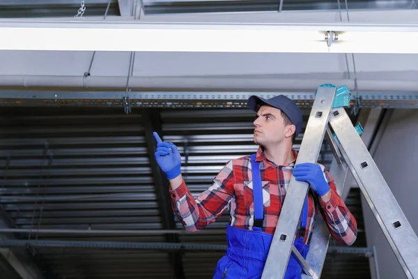 Primer plano de un electricista en una escalera reparando el cableado . — Foto de Stock