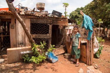Planaltina, Goias, Brezilya-Ekim 27, 2018: Genç bir çocuk Planaltina, Brasilia, Brezilya yakınındaki yoksul toplumda evinin yakınında bir tavuk kümesi önünde duruyor
