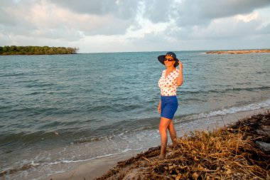 Mavi şapka ve kırmızı puantiyeli bluz Possing plajda giyen bayan