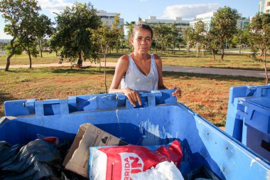Brasilia, D.F., Brezilya- 11 Haziran 2019: Fakir genç bir anne, çocuklarını beslemek için para kazanmak için başkent Brasilia'nın varlıklı bir semtinde çöpleri kazıyor.. 
