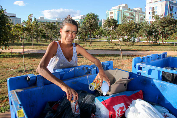 Brasilia, D.F., Brazil- June 11, 2019: A poor young mother digging through the Trash in an affluent neighborhood in the capital city of Brasilia, to try and earn some money to feed her kids. 