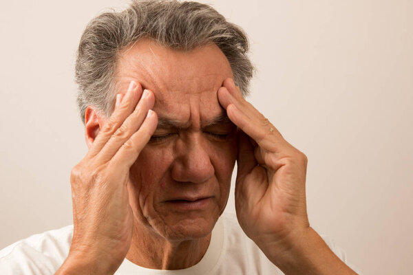 Senior Man in pain from a Headache rubbing his temples for relief 
