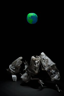 Plastik Dünya gezegeni, plastik bardaklardan, çatallardan ve kaşıklardan seçici bir ışıkla hayali yaratıkların el yapımı heykelleri. Dünya Saati, Dünya Günü, Okyanus Günü ve diğer ECO tarihleri için ekoloji kavramı.