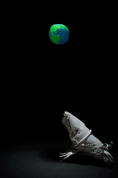 Plastik Dünya gezegeni plastik bardaklar, çatallar ve kaşıklar arasından seçici bir ışıkla hayali bir yaratığın el yapımı heykeli. Dünya Saati, Dünya Günü, Okyanus Günü ve diğer ECO tarihleri için ekoloji kavramı.