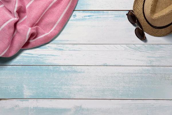 Towel. Scarf. Cover for picnic. Sunglasses. Straw hat. Summer travel concept elements. On turquoise wooden table. Top view.