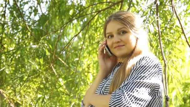 Menina grávida. Uma mulher grávida no parque. Mulher falando ao telefone — Vídeo de Stock