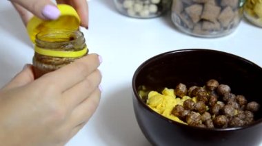 kahvaltılık gevrek, kahverengi bir kase çikolata topları için bal dökün. Sağlıklı kahvaltı. Diyet Kase ve beyaz arka plan üzerinde izole mısır gevreği ile kaşık