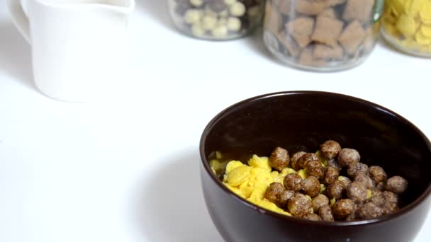 Verser le miel dans les céréales pour le petit déjeuner, les boules de chocolat dans un bol brun. Petit déjeuner sain. Bol diététique et cuillère avec flocons de maïs isolés sur fond blanc — Video