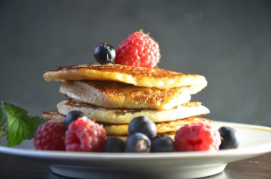 Siyah bir arka plan üzerinde ahududu ve yaban mersini ile çilek ve akçaağaç şurubu ile Krep