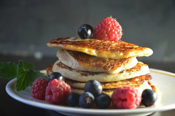 Pfannkuchen mit Beeren und Ahornsirup mit Himbeeren und Blaubeeren auf schwarzem Hintergrund — Stockfoto