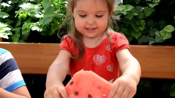 Забавный портрет невероятно красивой маленькой девочки, которая ест арбуз, здоровую фруктовую закуску, очаровательного ребенка-малыша с вьющимися волосами. — стоковое видео