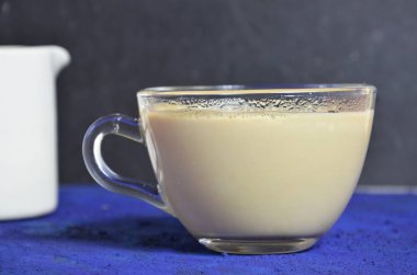kahve ve krema ile şeffaf cam fincan. arka planda sütçü. karanlık anahtar